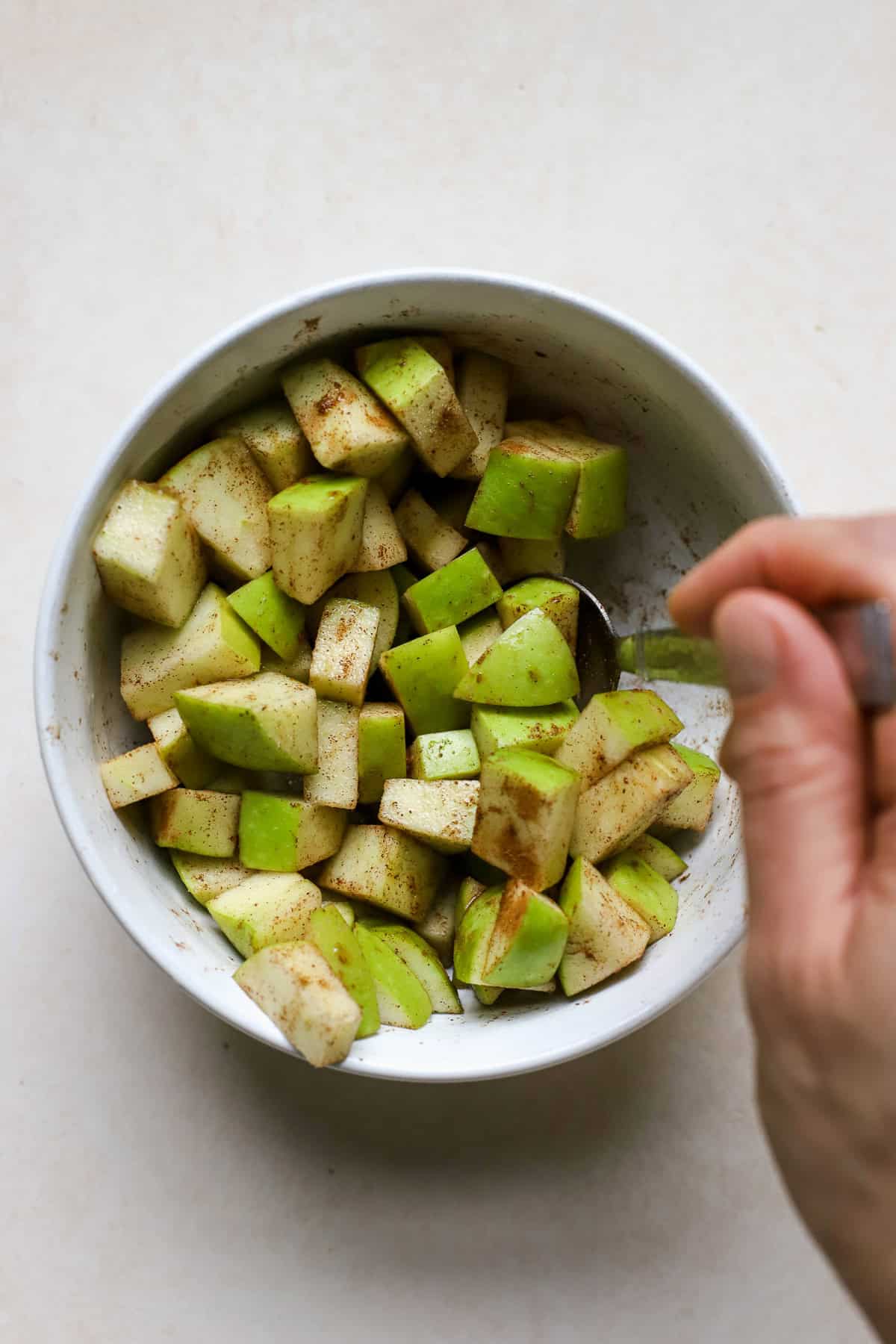 Stirring together diced Granny Smith apple with cinnamon, maple syrup, lemon juice, and salt.