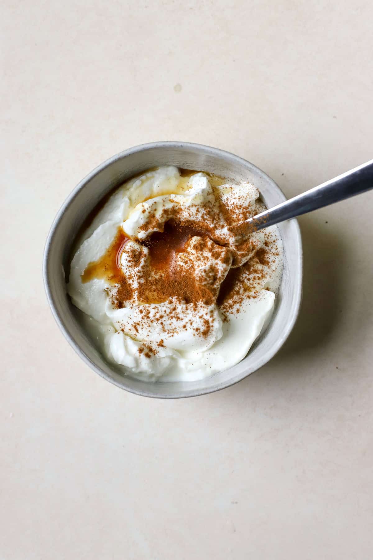Bowl of Greek yogurt with cinnamon, maple syrup, and vanilla extract before being mixed together.