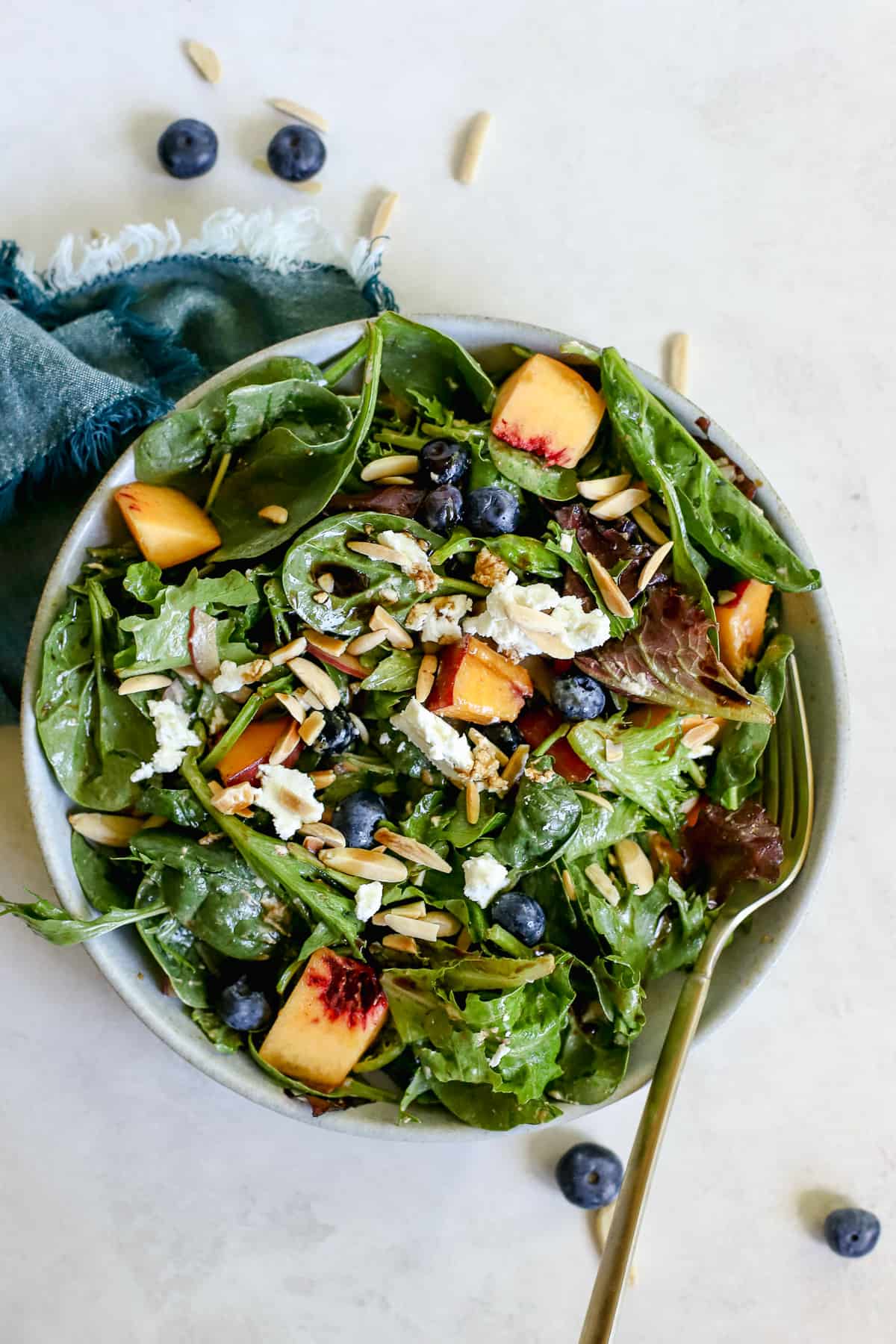 Peach blueberry salad in light blue bowl with teal linen on gray and white surface