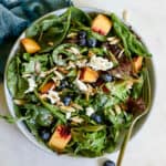 Peach blueberry salad in light blue bowl with teal linen on gray and white surface