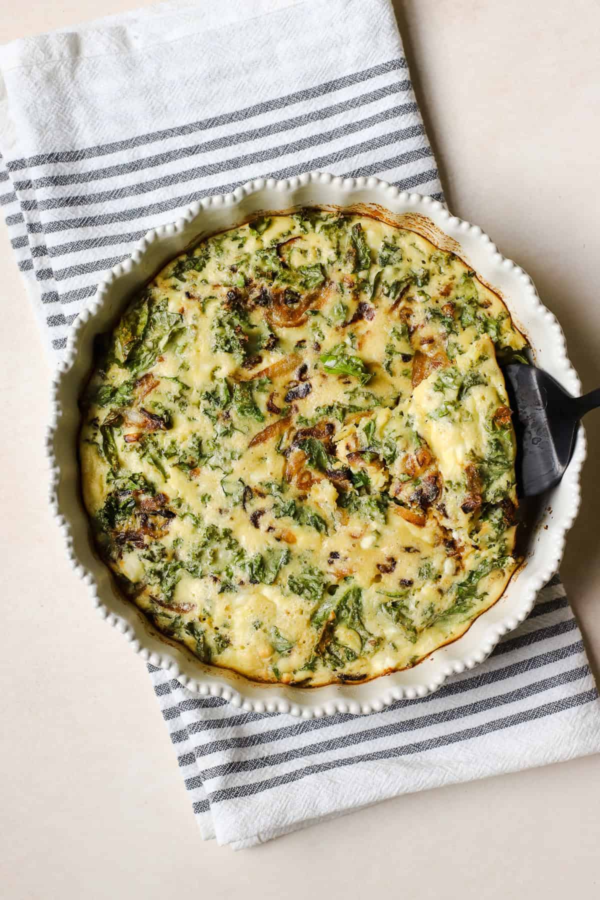 Crustless kale pie with spatula lifting a piece.