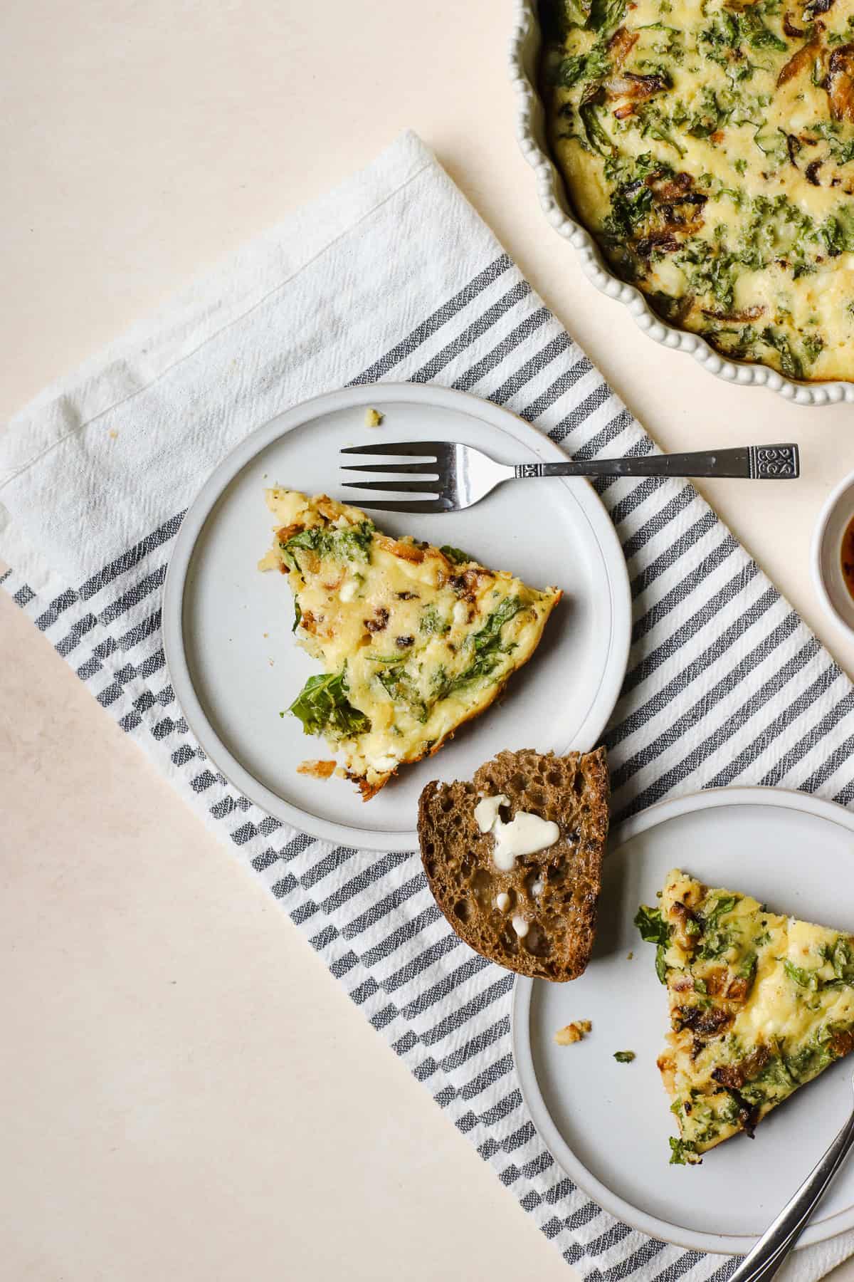Slices of crustless kale pie on small plates with forks and a piece of toast.