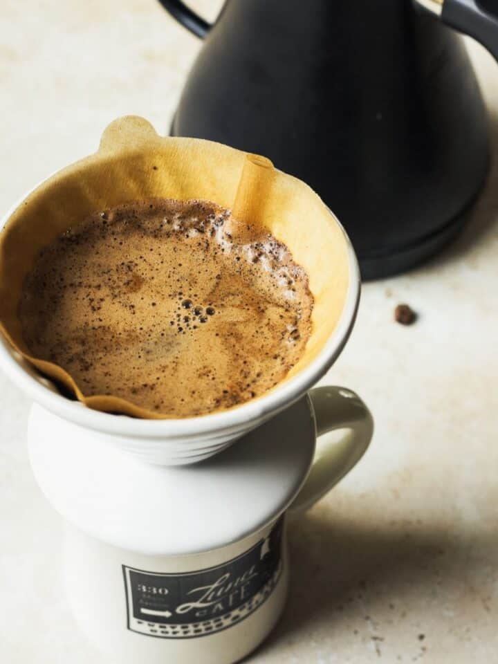 Pour over coffee being brewed in a mug next to gooseneck kettle.