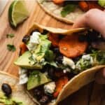 Vegetarian black bean tacos with carrots and lime on serving board.