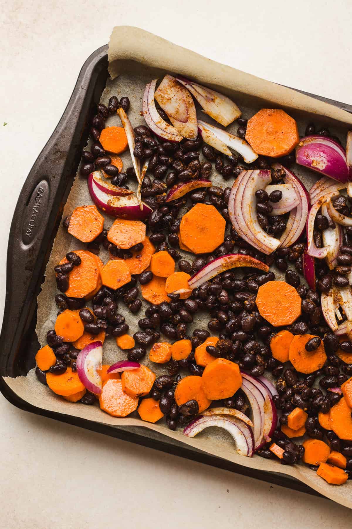 Taco-seasoned black beans, carrots, and onions on sheet pan before baking.
