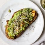 Avocado toast with everything bagel seasoning on white plate.