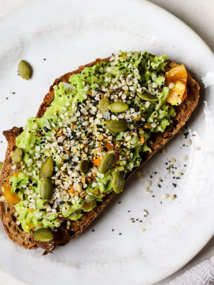 Avocado toast with everything bagel seasoning on white plate.