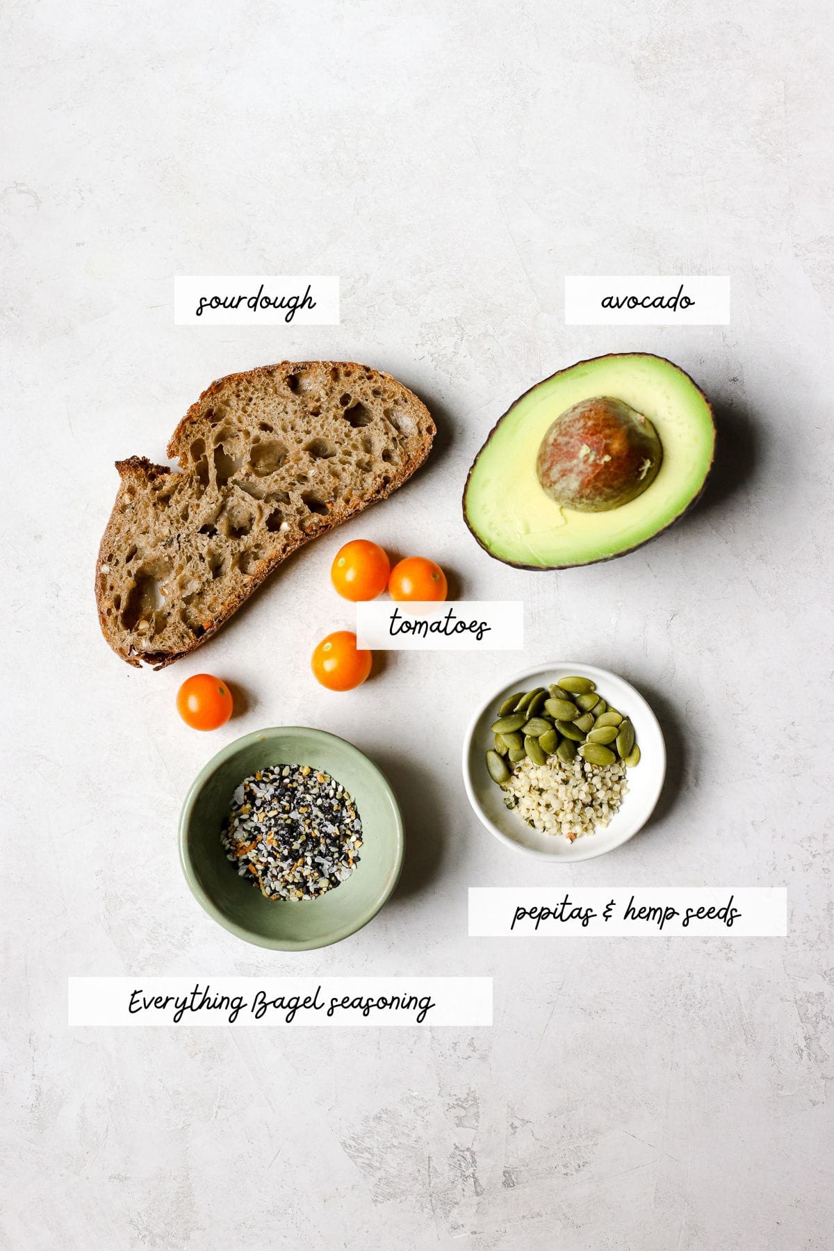 Avocado toast with everything bagel seasoning ingredients, including sourdough, avocado, tomato, everything seasoning, hemp seeds, and pepitas.