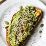 Avocado toast with everything bagel seasoning on white plate.