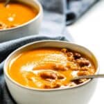 Thai butternut squash soup in small white bowl with spoon.