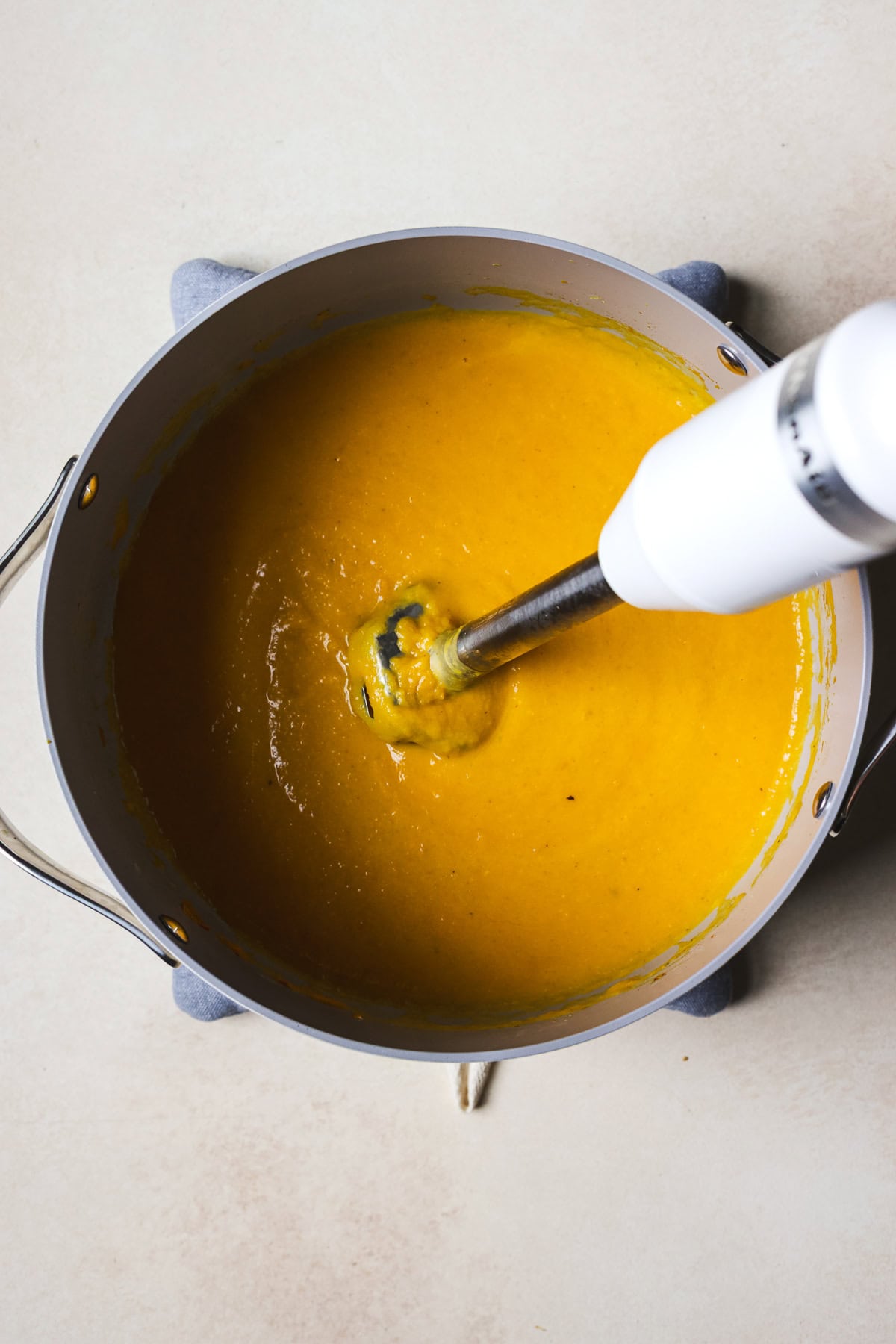 Blending Thai butternut soup using an immersion blender.