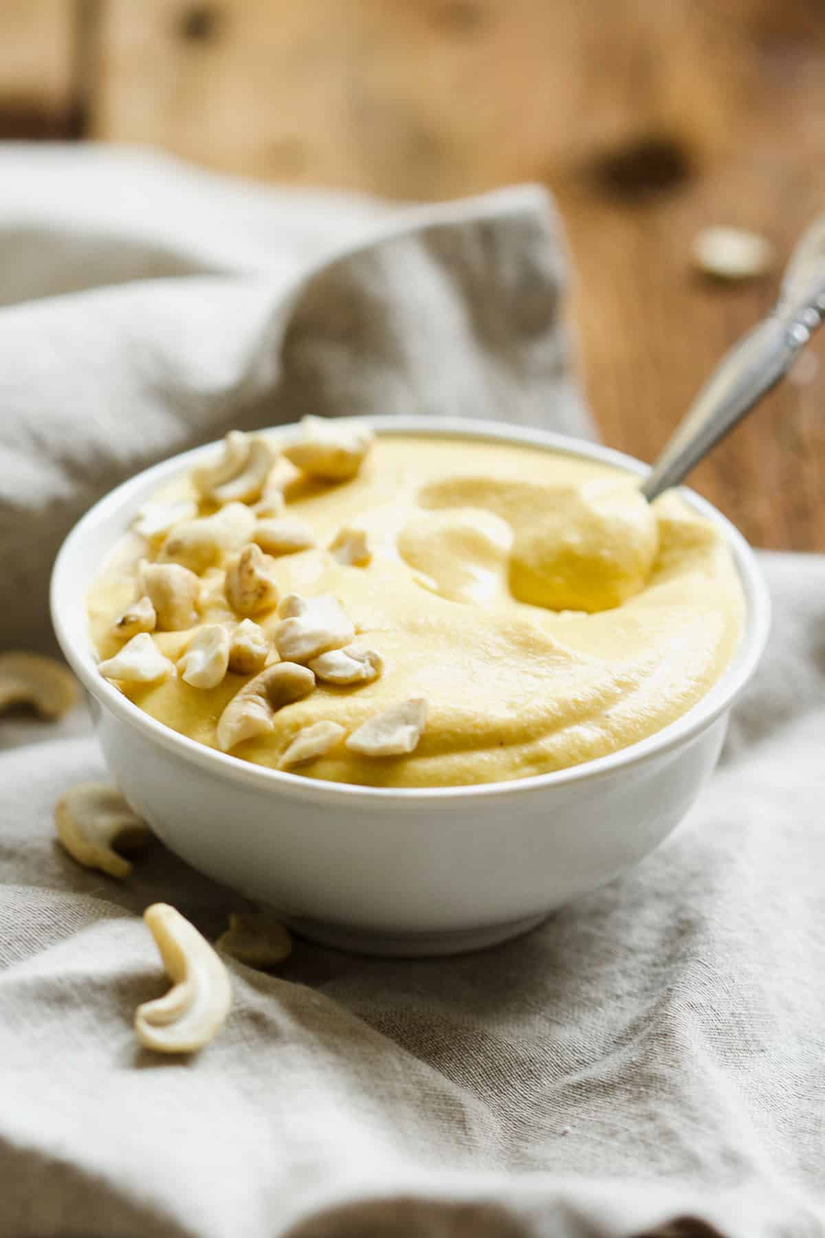 Butternut cashew sauce in small white bowl with spoon.