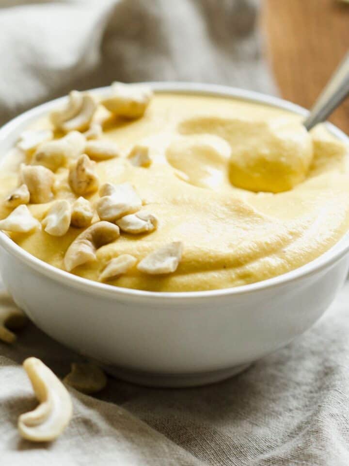 Butternut cashew sauce in small white bowl with spoon.