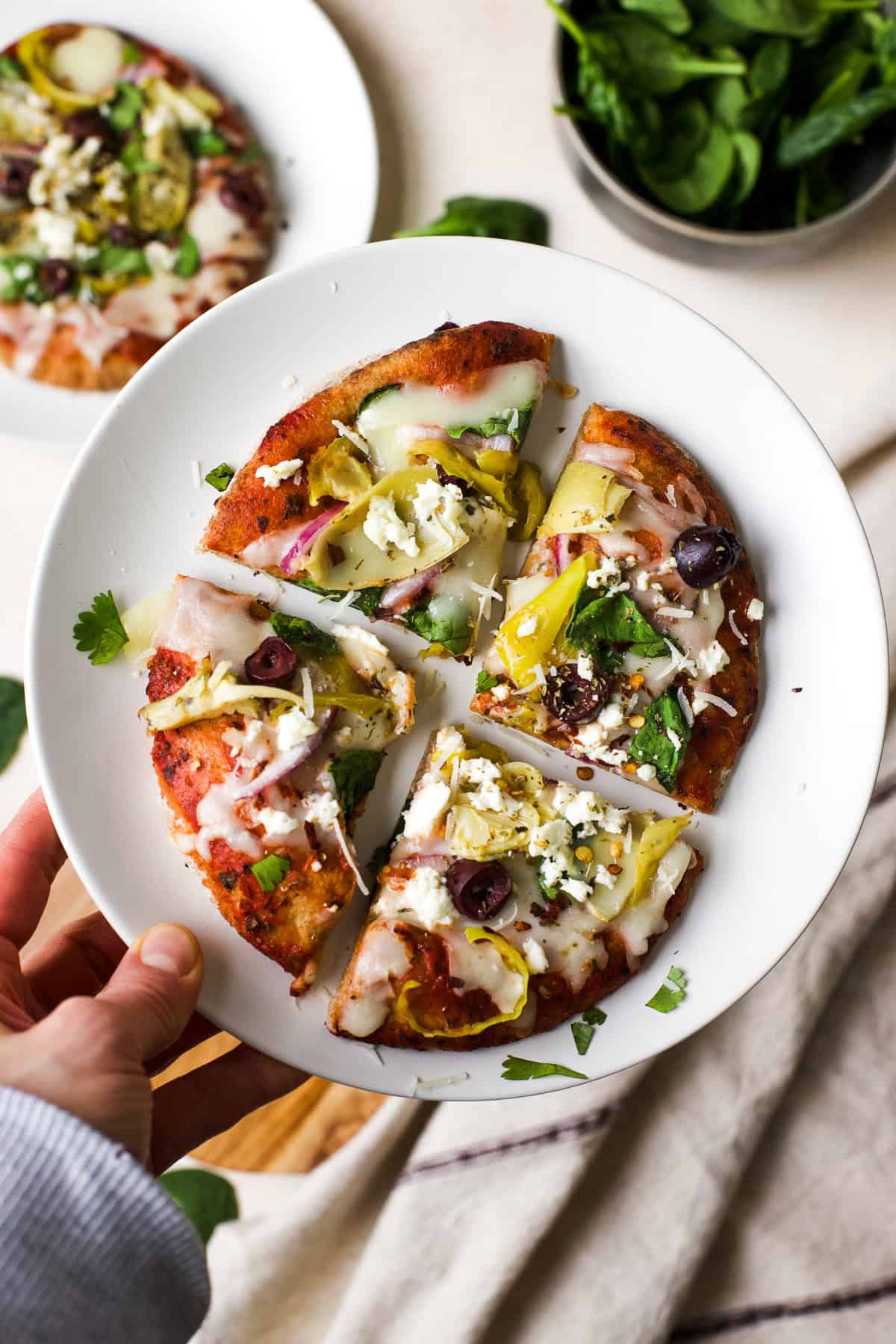 Greek pita pizza slices on white plate.