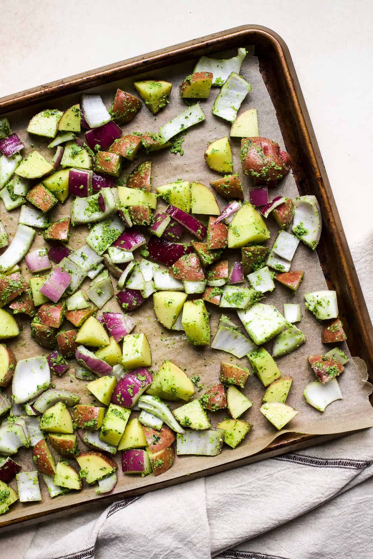 Potatoes seasoned with pesto on a sheet pan.