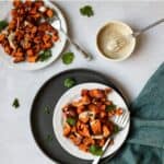 Harissa roasted sweet potatoes drizzled with tahini sauce on a plate.