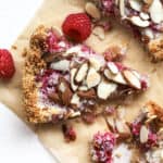 Three pieces of raspberry almond macaroon tart on parchment paper with fork