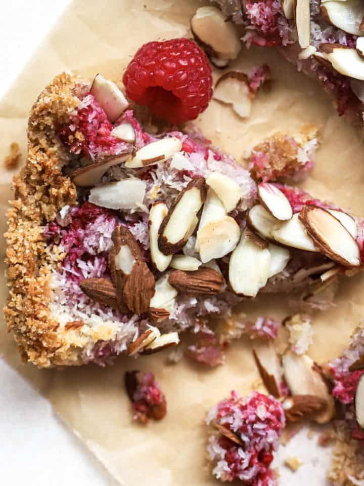 Three pieces of raspberry almond macaroon tart on parchment paper with fork