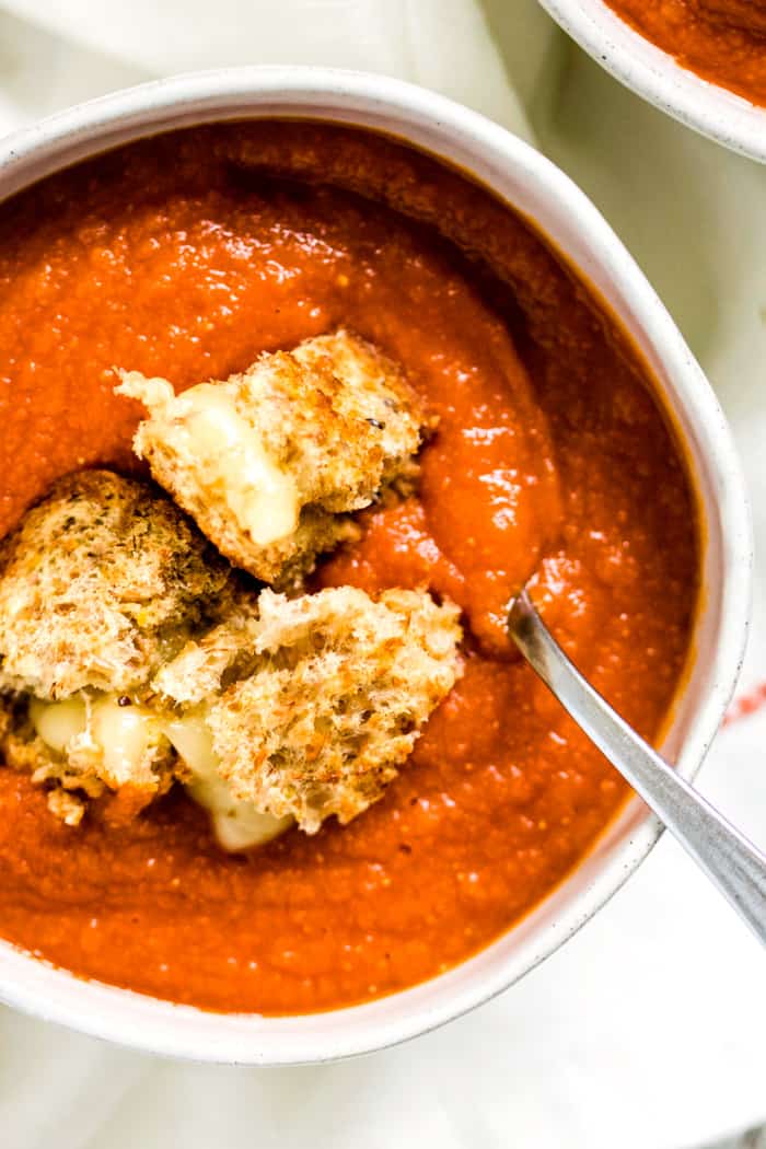Spicy tomato lentil soup in a bowl topped with grilled cheese cubes for a cozy vegetarian dinner.