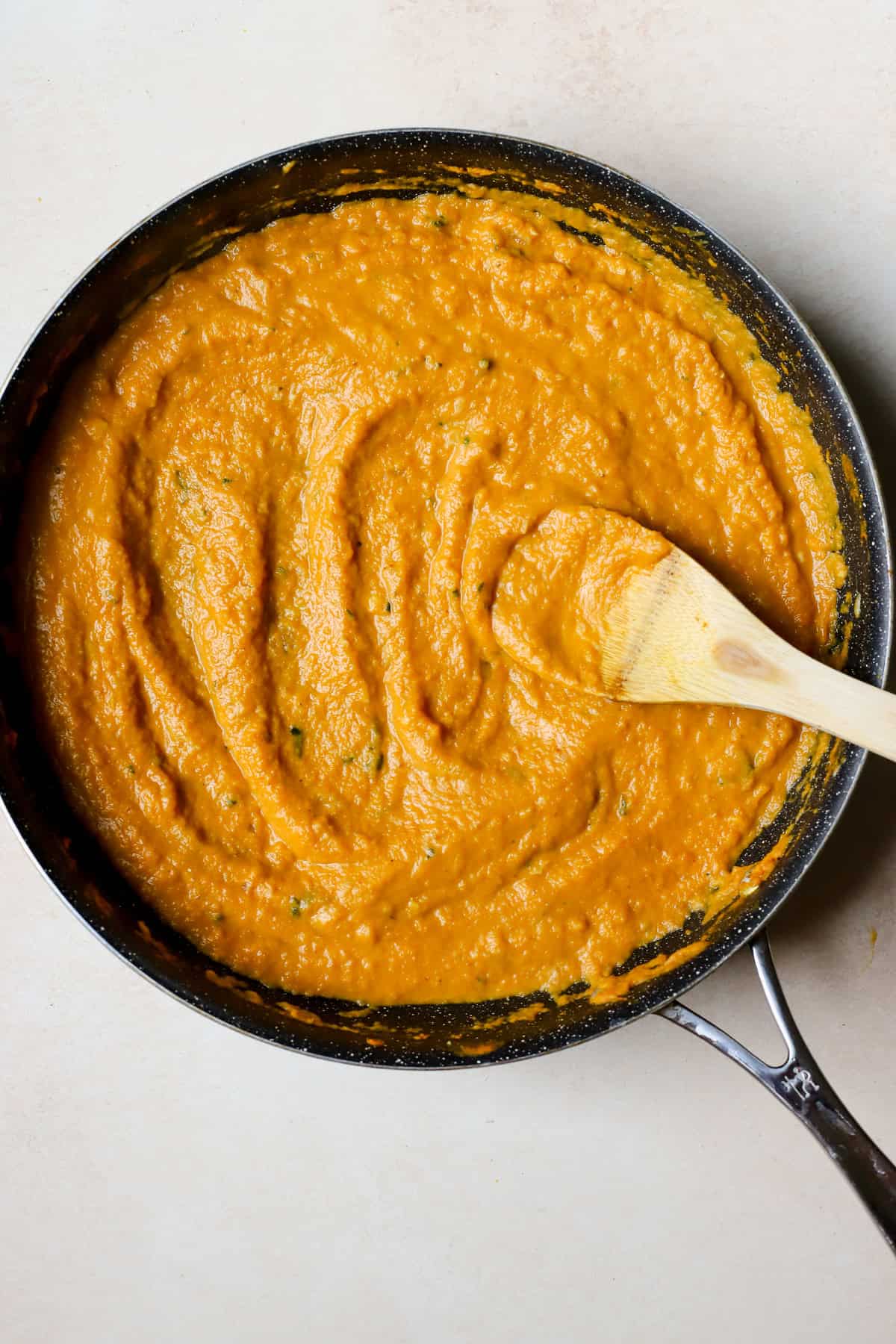 Fresh homemade pumpkin sauce in skillet with bamboo spoon.
