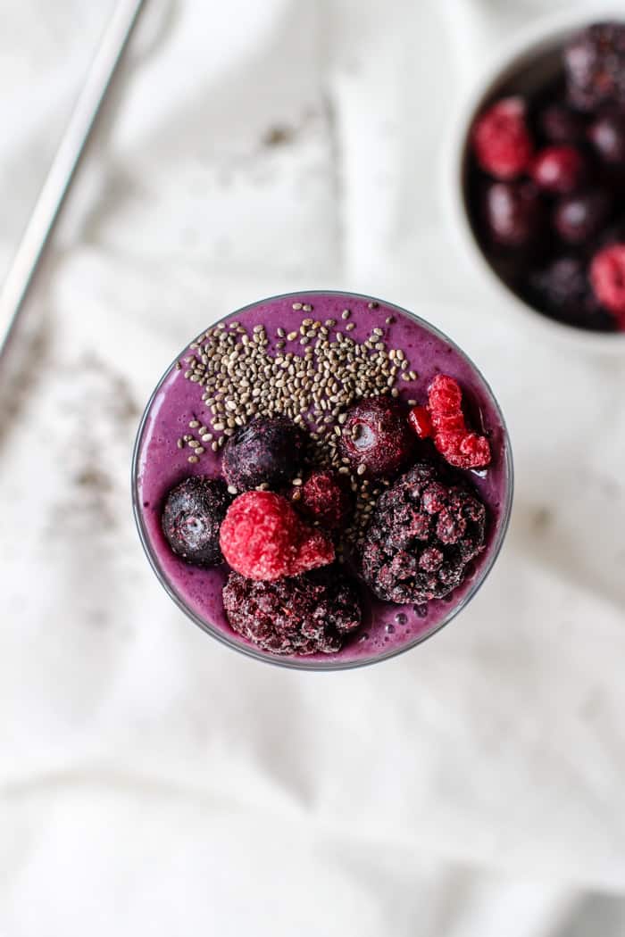 Berry vanilla protein smoothie in a glass with a steel reusable straw