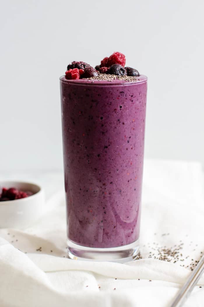 Berry vanilla protein smoothie in a glass with a steel reusable straw