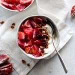 Blood orange maple pecan yogurt bowl in white bowl on white napkin