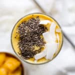 Mango turmeric ginger smoothie topped with chia seeds and coconut flakes