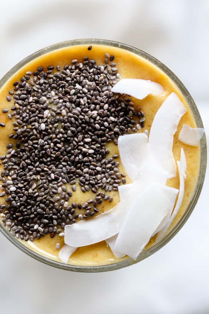 Mango turmeric ginger smoothie topped with chia seeds and coconut flakes