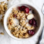 Maple cranberry almond granola in a small white bowl with almond milk