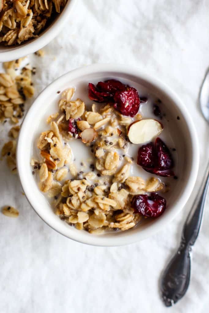 Maple cranberry almond granola in a small white bowl with almond milk