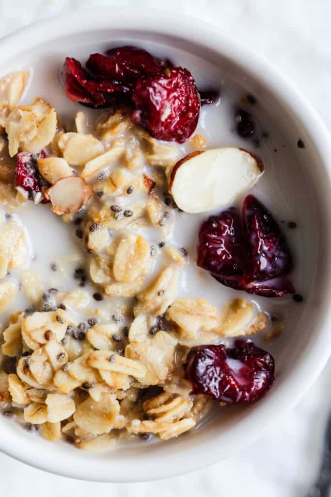 Maple cranberry almond granola in a small white bowl with almond milk