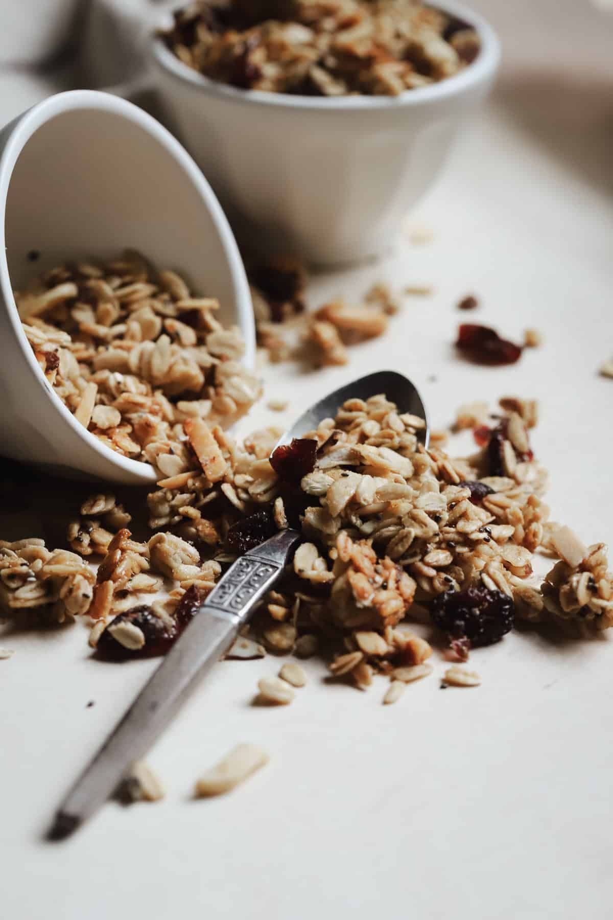 Almond cranberry granola spilling out of bowl onto spoon.