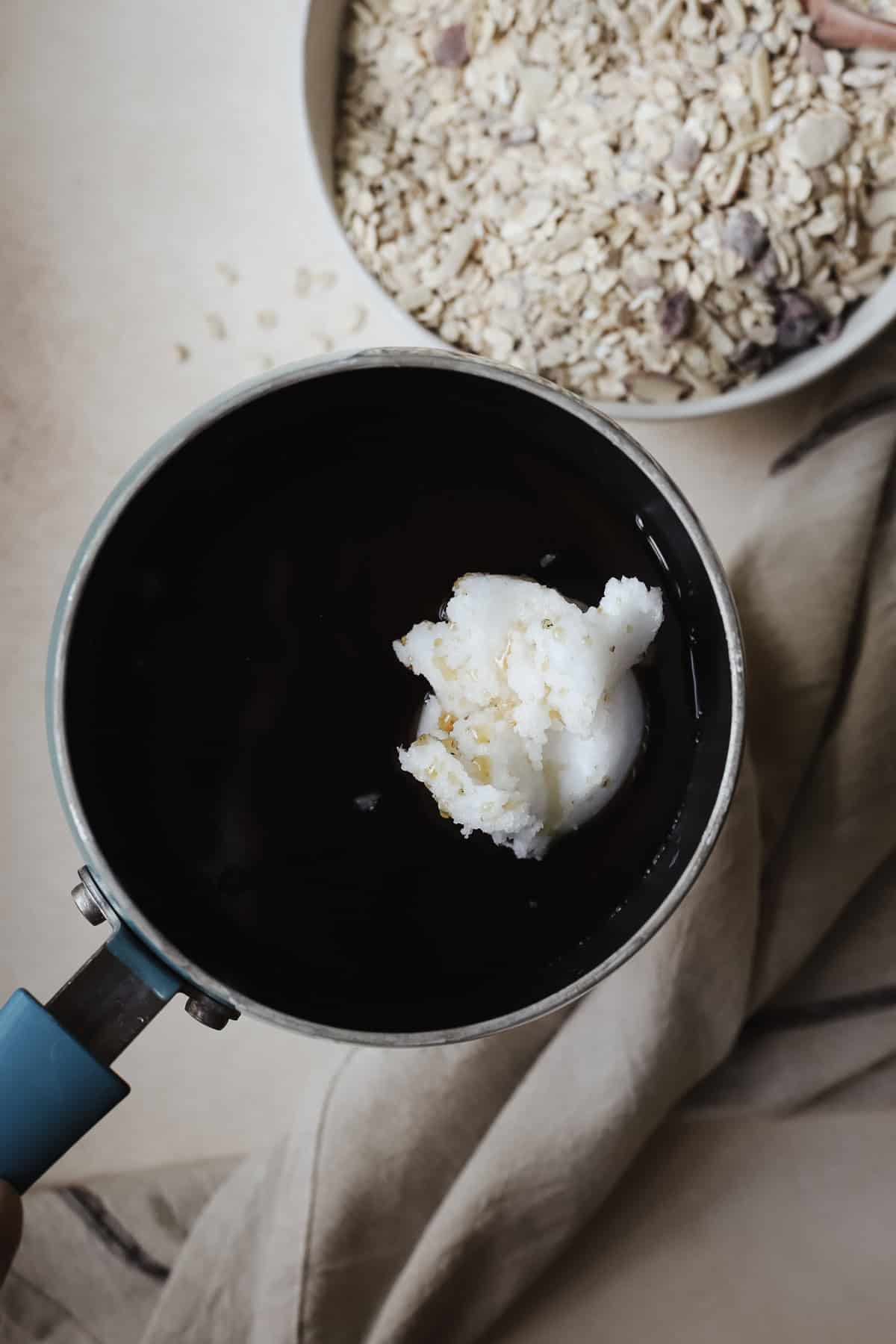 Melting coconut oil and maple syrup together in a small pot.