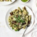 Pesto pasta salad with chicken on a white plate.