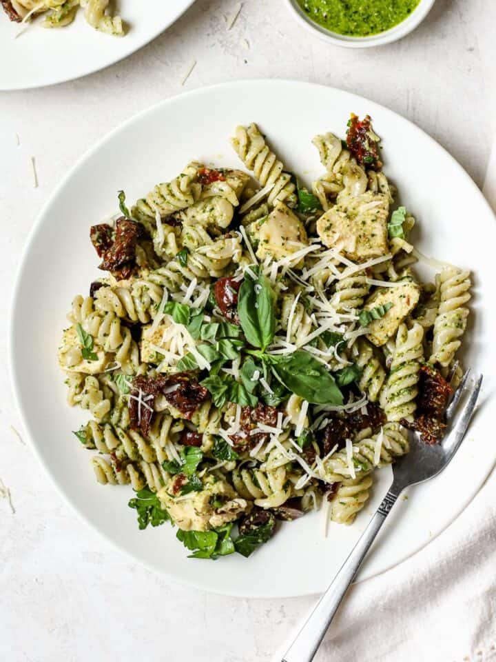 Pesto pasta salad with chicken on a white plate.