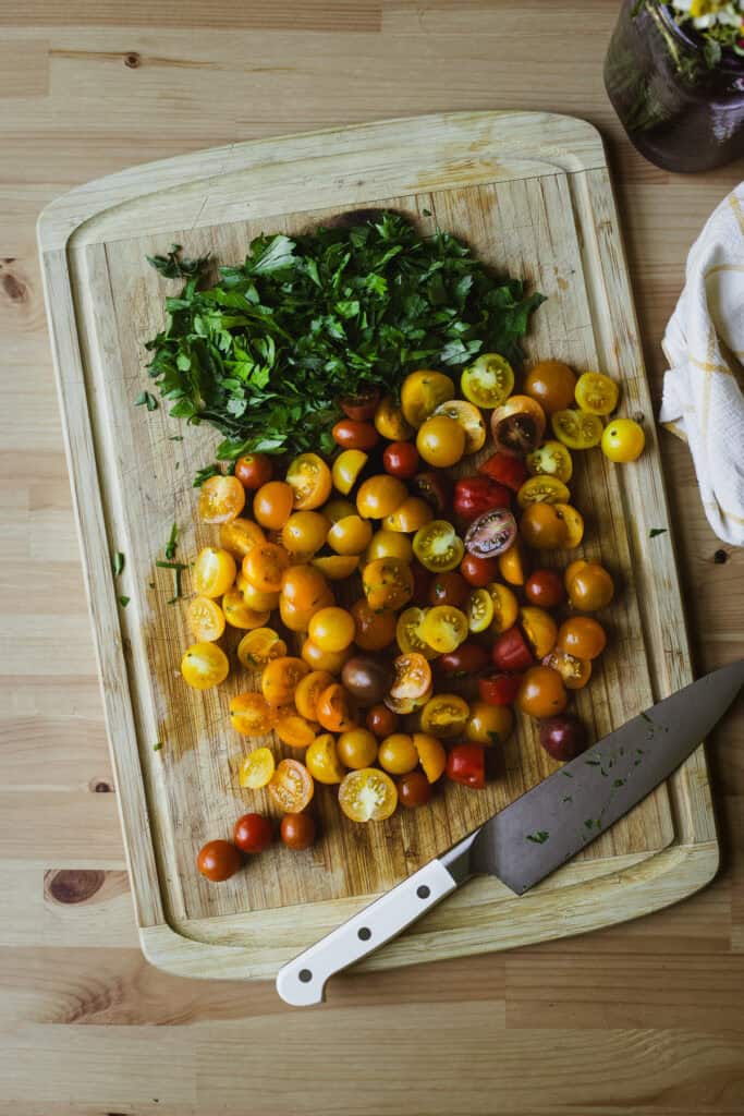 Chopped parsley and tomatoes on a wooden cutting board.