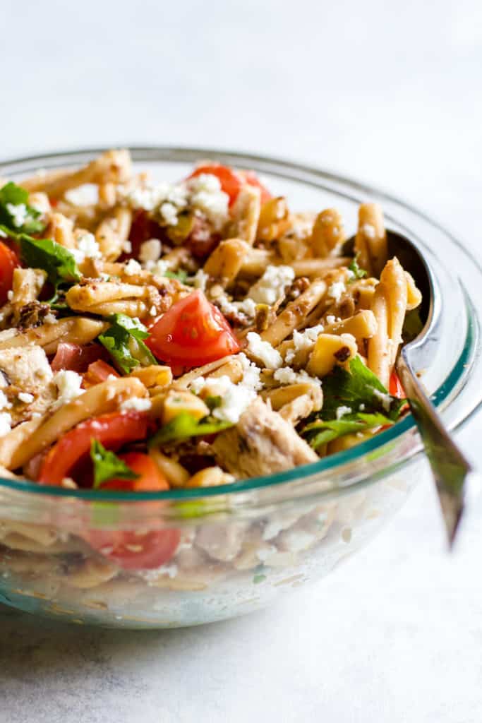Olive tapenade and tuna pasta salad in clear bowl with spoon
