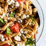 Olive tapenade and tuna pasta salad in clear bowl with spoon