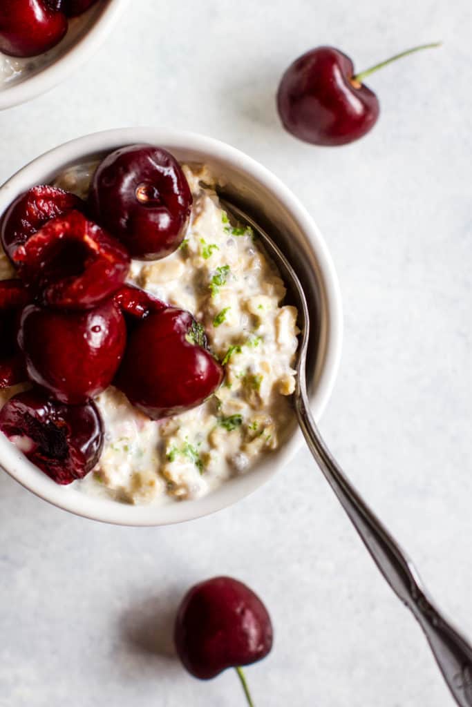 Cherry lime overnight oats in small white bowl with spoon