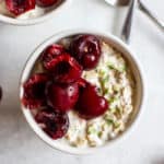 Cherry lime overnight oats in small white bowl with spoon