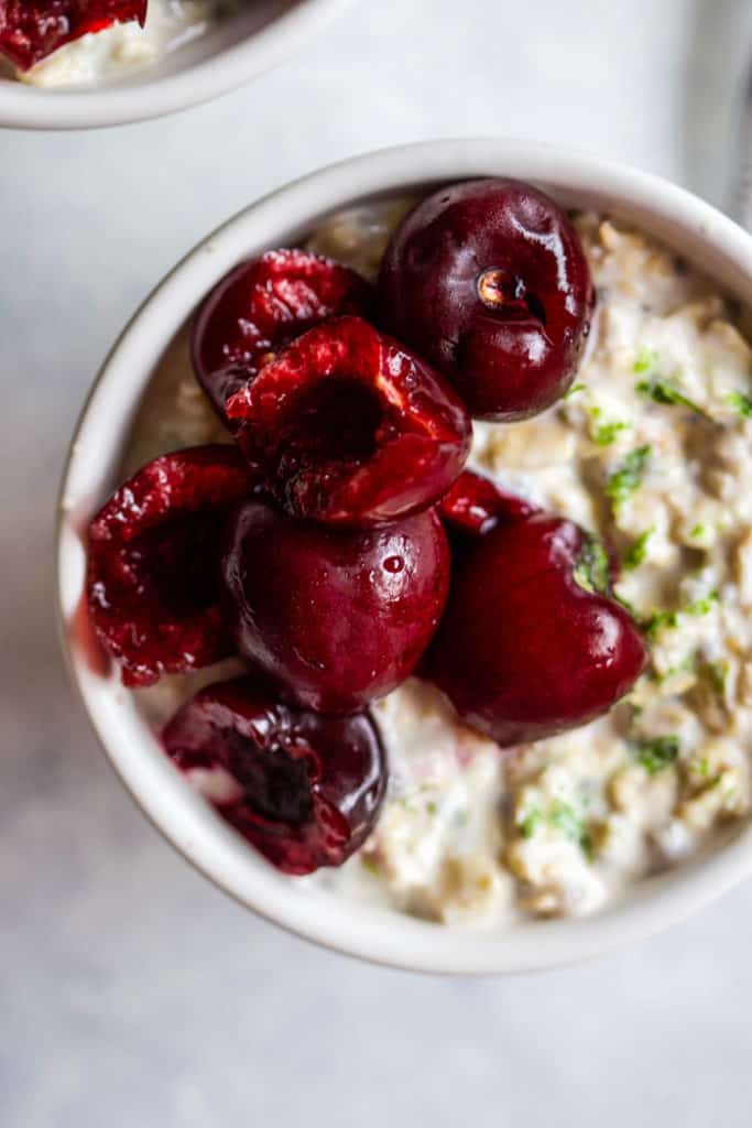 Cherry lime overnight oats in small white bowl with spoon