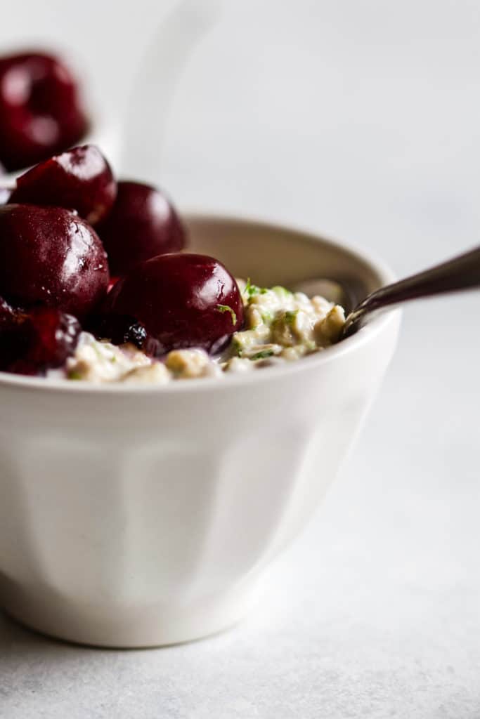 Cherry lime overnight oats in small white bowl with spoon