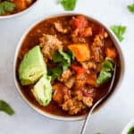 Sweet potato turkey chili in white bowl with cilantro and avocado topping