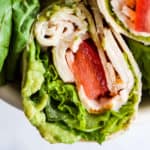 Whole wheat turkey wraps in white bowl with romaine lettuce leaves