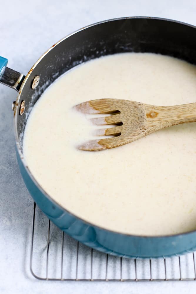 Mac and cheese sauce in blue sauté pan on cooling rack