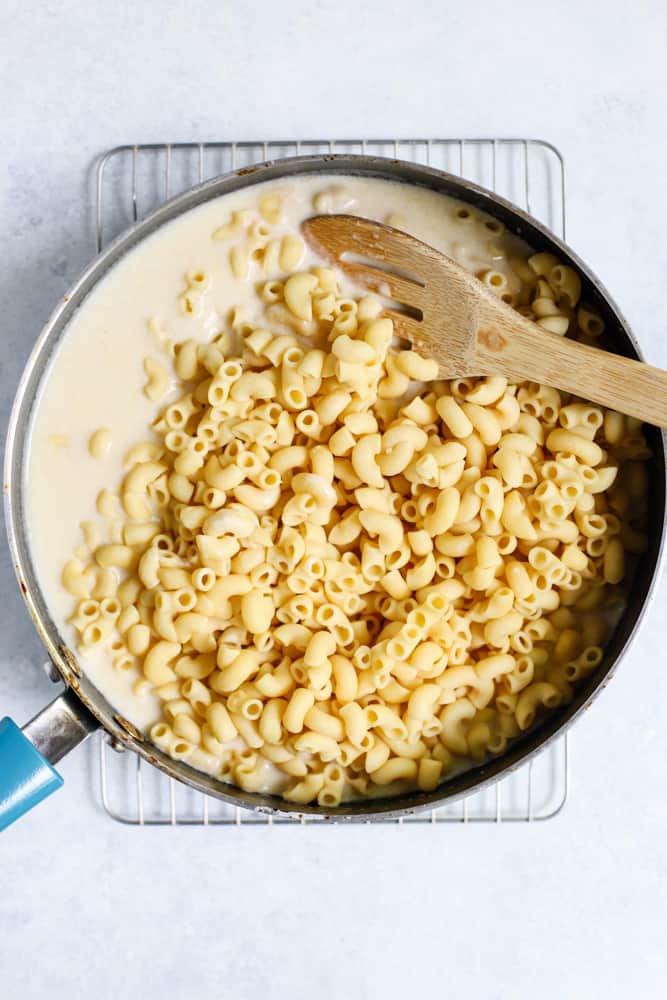 Elbow noodles being folded into mac and cheese sauce in sauté pan