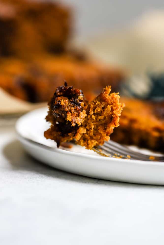 Bite of healthy pumpkin chocolate chip bread on fork resting on white plate