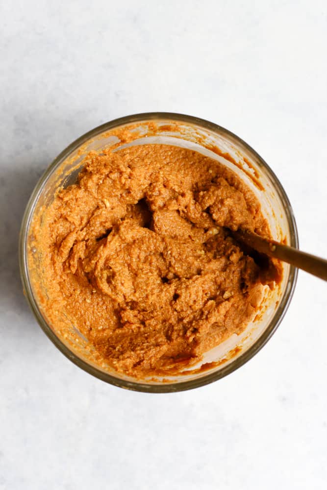 Pumpkin, egg, vanilla, butter, and maple syrup mixed together in clear mixing bowl