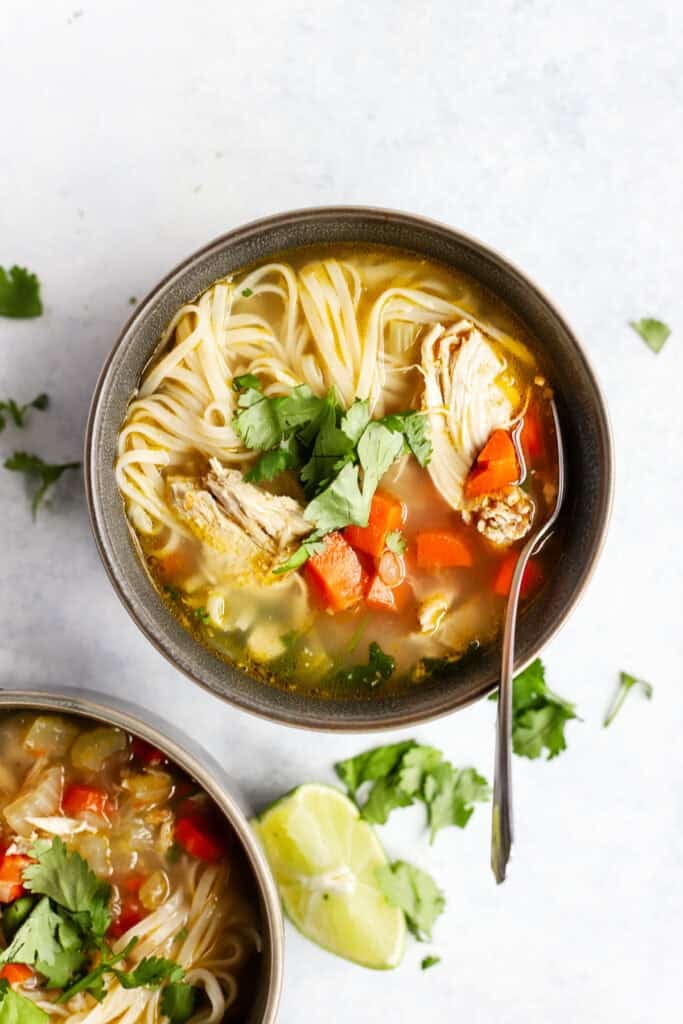 Ginger lime chicken soup with rice noodles in a bowl.